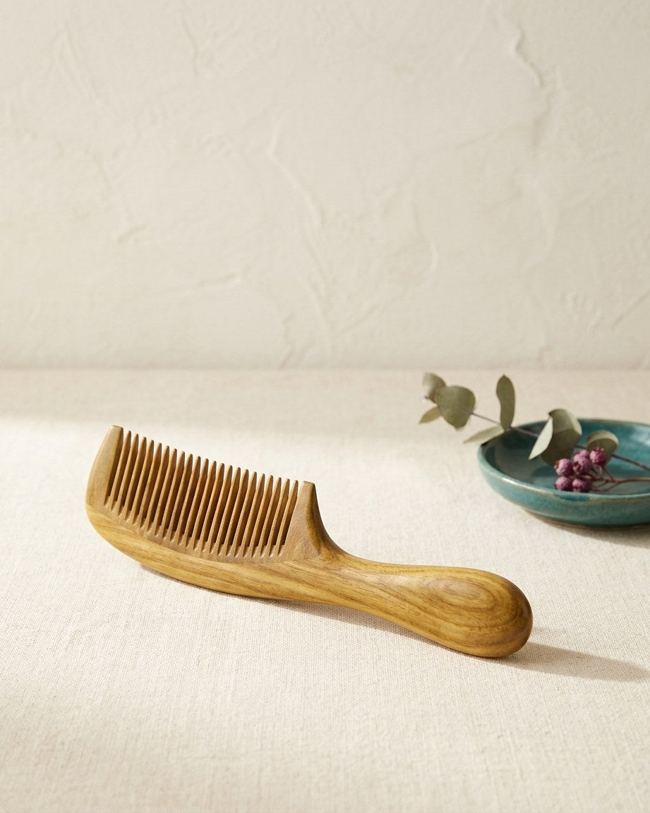 Sandalwood scalp massage comb on a cream linen table